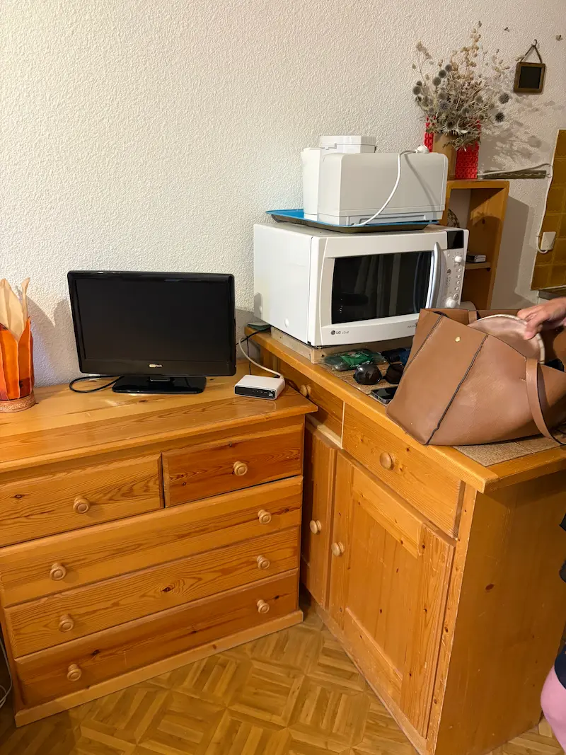 Le coin cuisine : micro-ondes et meubles en pin, à côté de la télévision